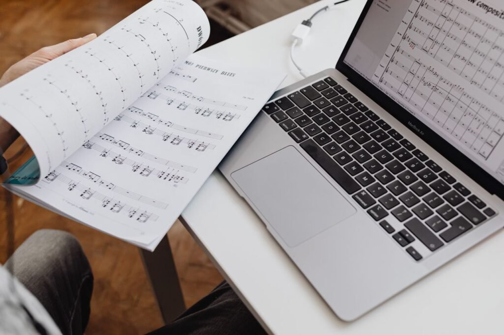 A detailed view of sheet music beside a laptop on a desk, ideal for music composition themes.